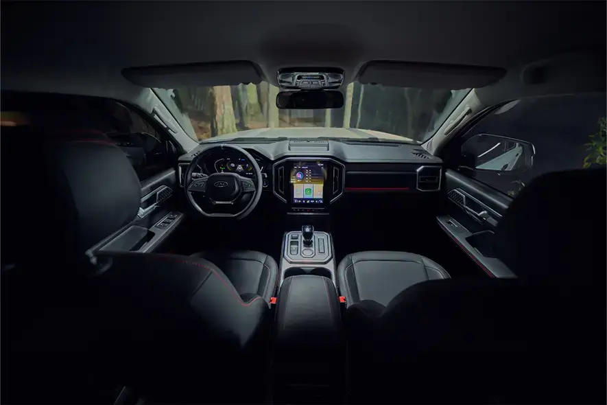 Diseño interior de modelo JAC T9 mostrando asientos delanteros, pantalla inteligente, volante y tablero.