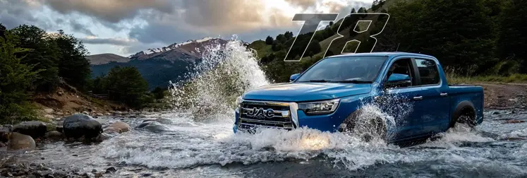 Pick-Up JAC T8 4x4 andando en río  con montañas de fondo.